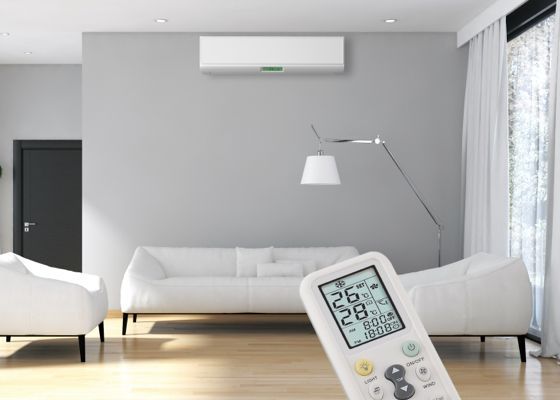 Salon avec canapé blanc, climatiseur et télécommande indiquant la température.