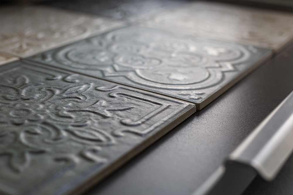Dekorative, geprägte Metallpaneele mit kunstvollen, geschwungenen Mustern auf einer dunklen Tischplatte