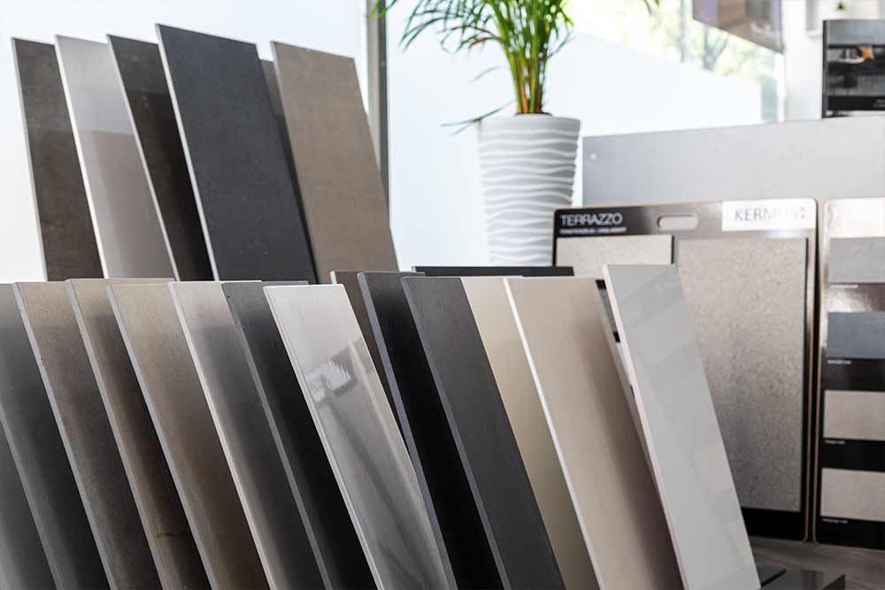 Ausstellung verschiedener großer rechteckiger Materialmuster in Grau, Schwarz und Beige in einem Ausstellungsraum