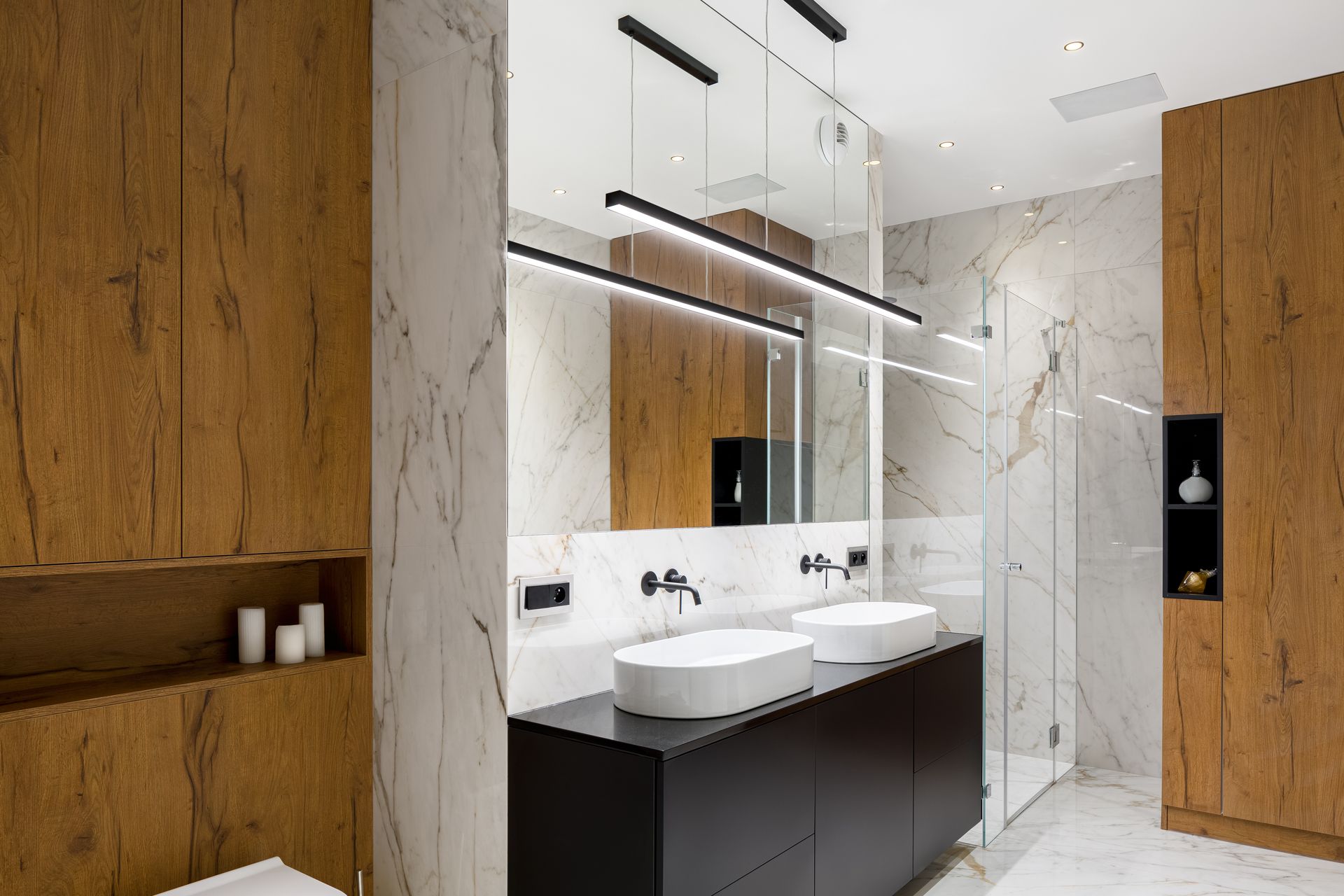 Modernes Badezimmer mit weißen Marmorwänden, Doppelwaschbecken, großem Spiegel, Glasdusche und Holzschränken