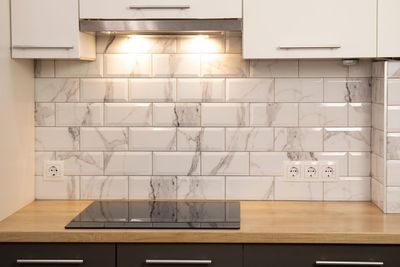 Eine Küche mit Herd und Backofen und einer Wand aus Marmorfliesen.