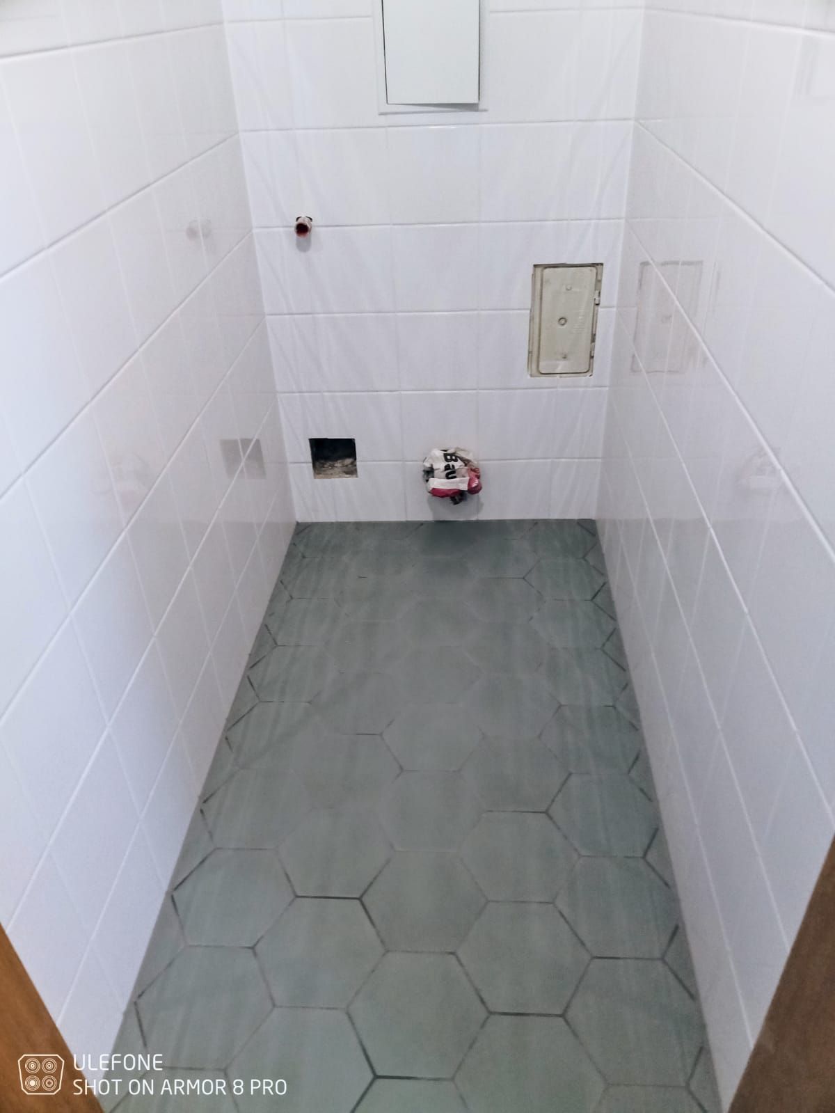 Ein Badezimmer mit weißen Fliesen und einem sechseckigen Fliesenboden.