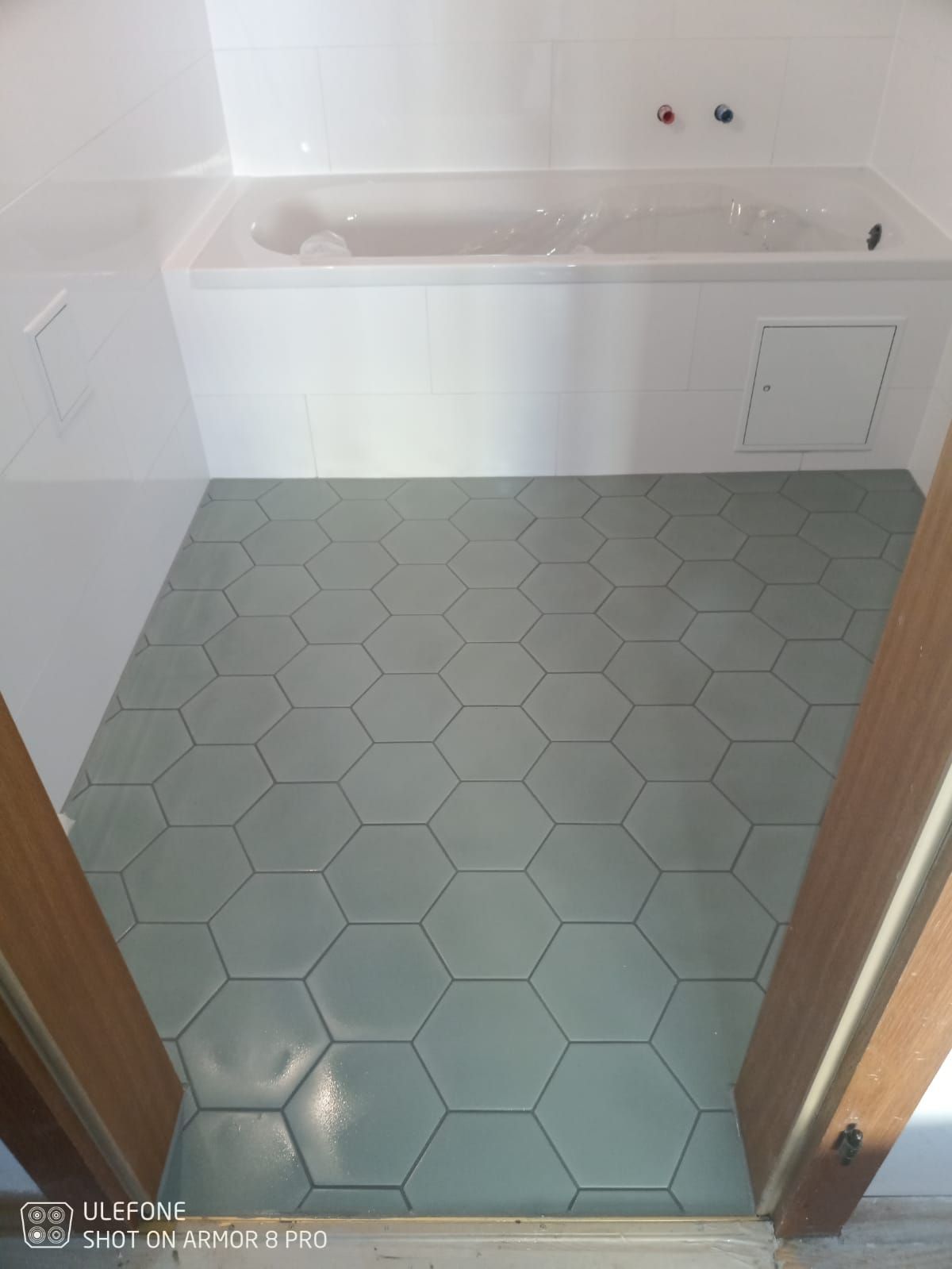 Ein Badezimmer mit Badewanne und sechseckigem Fliesenboden.