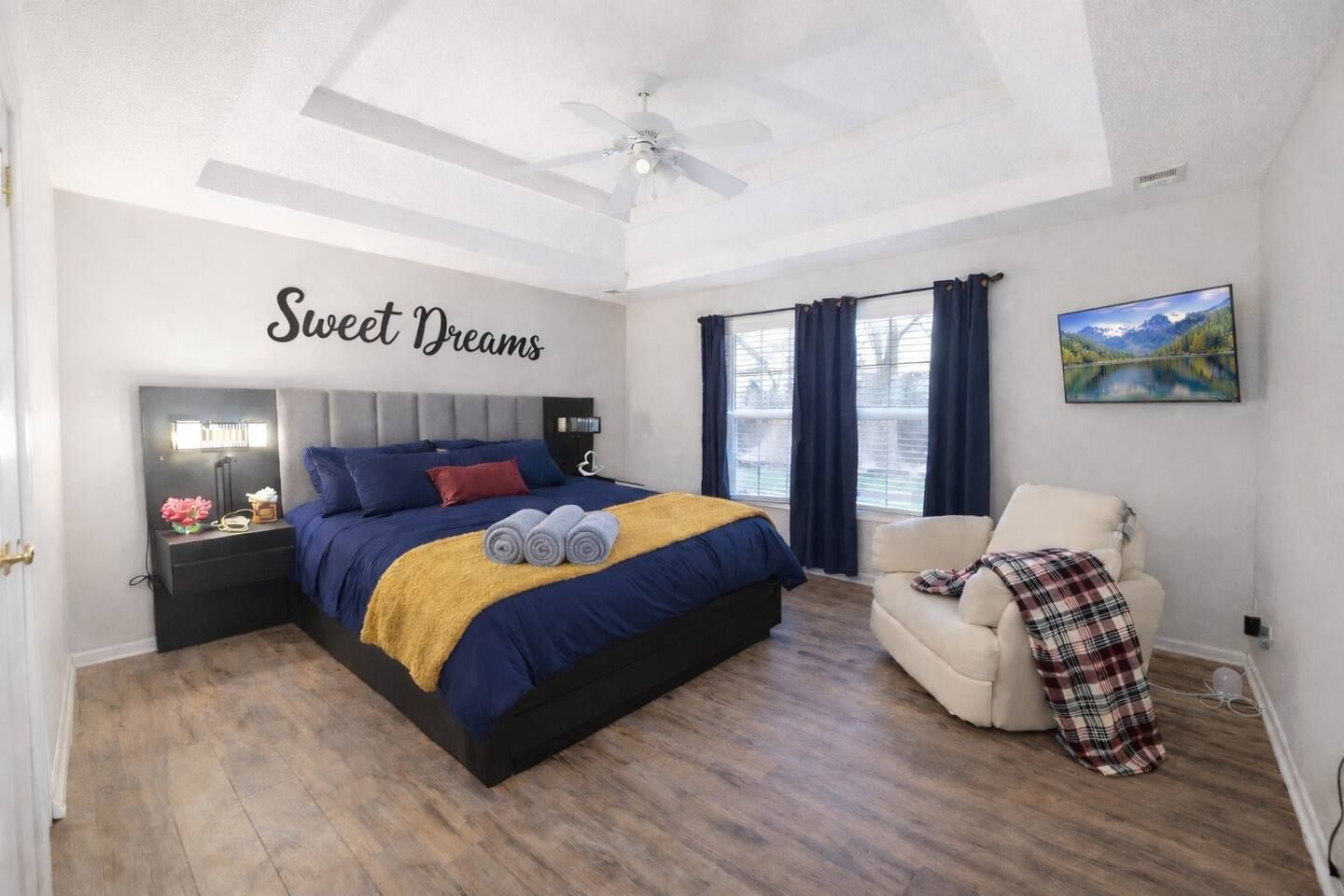 Bedroom with a bed, a recliner, and a TV; blue and yellow bedding.