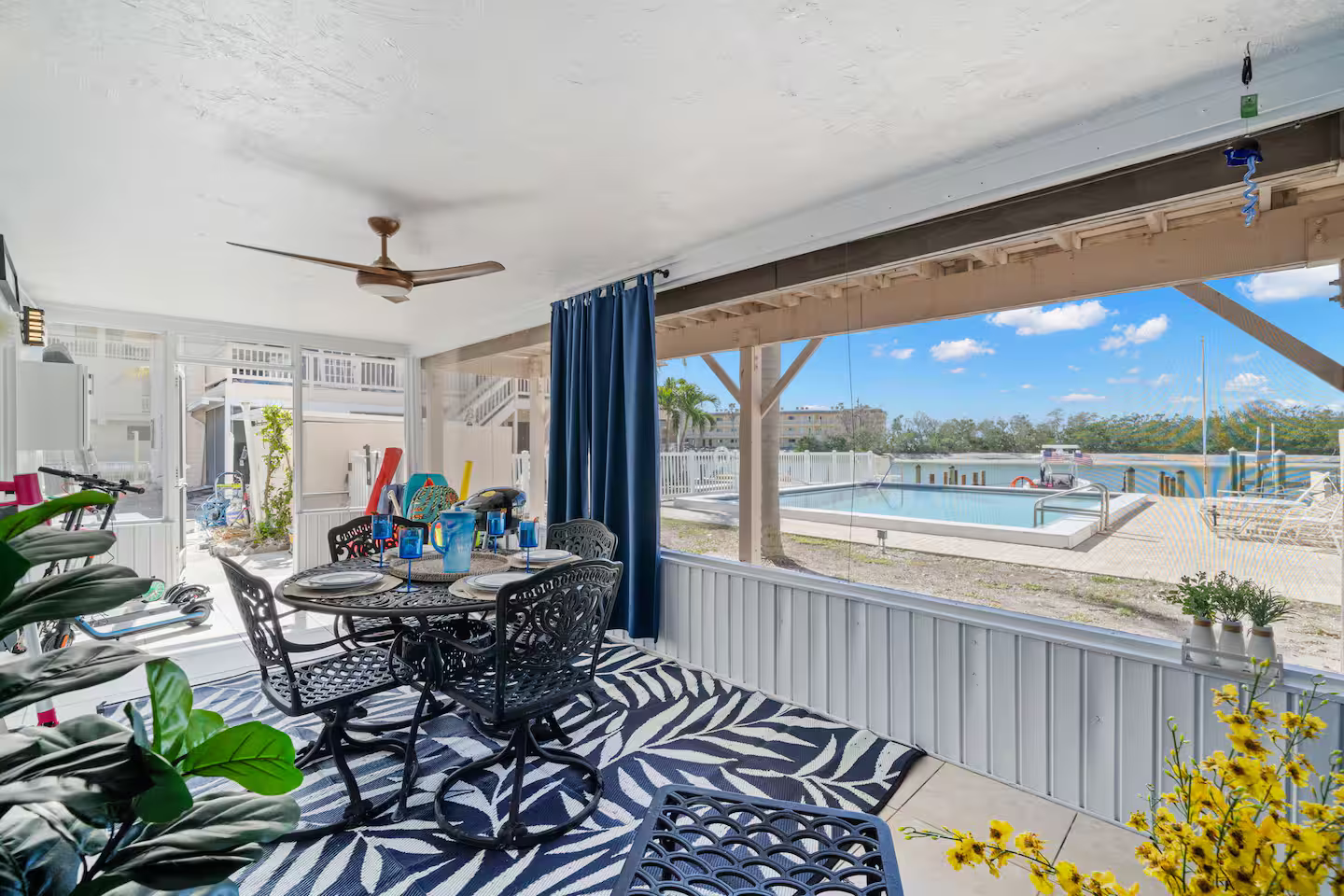 A patio with a table and chairs and a view of a pool.