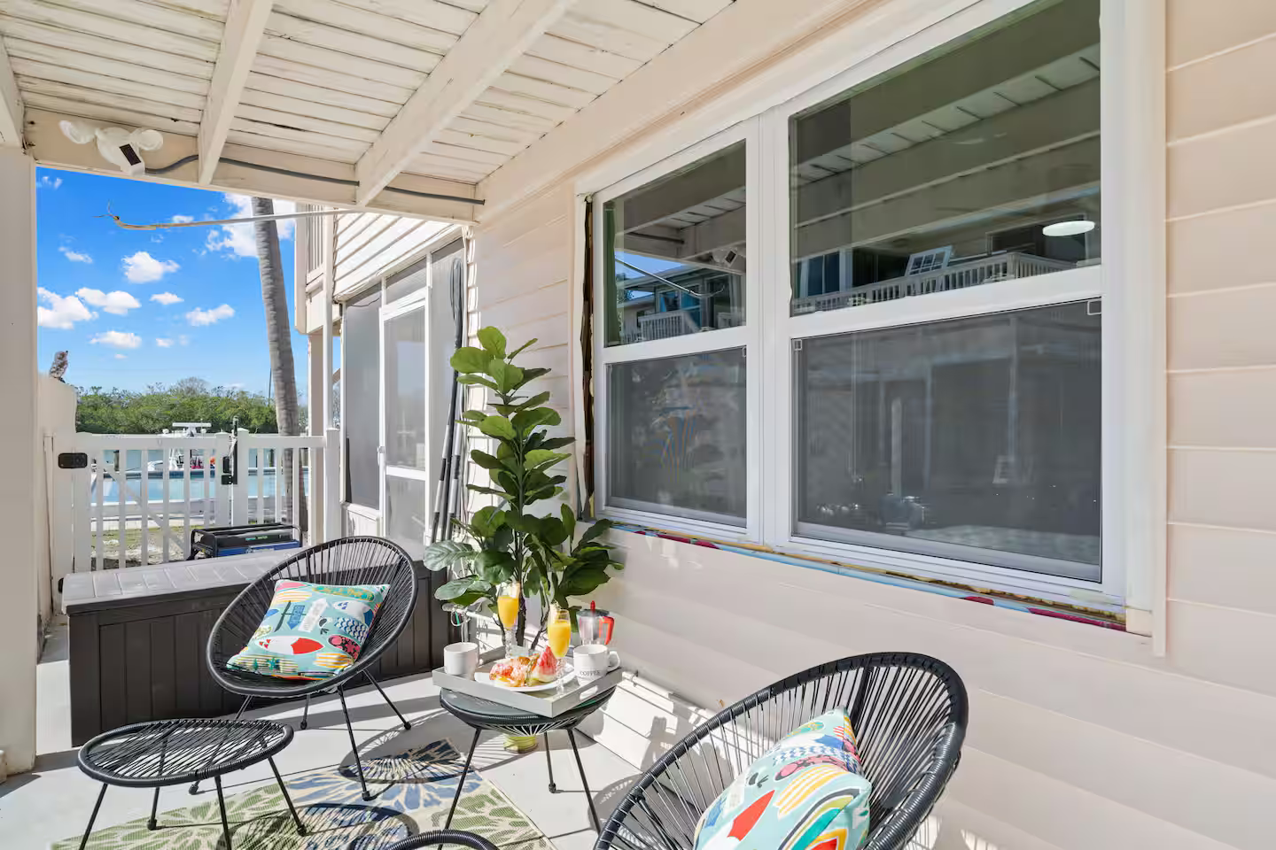 A porch with chairs and a table with a view of the ocean.