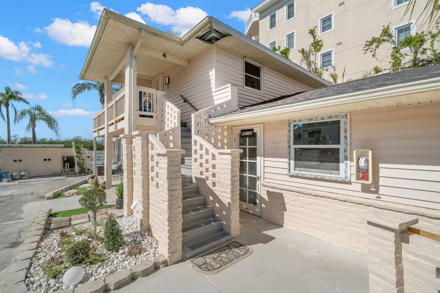 A white house with stairs leading up to the second floor.