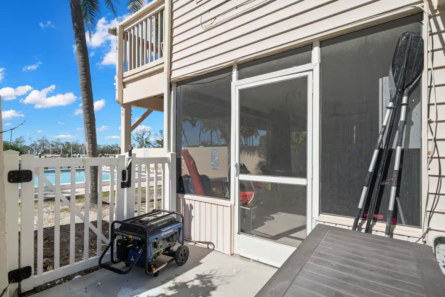 A generator is parked on the side of a screened in porch.
