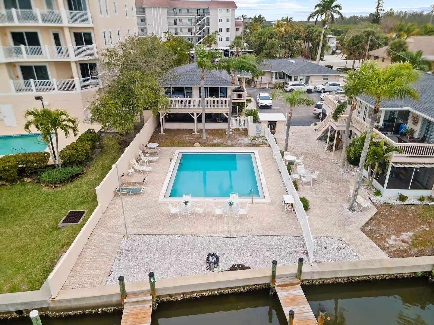 An aerial view of a large swimming pool surrounded by buildings and palm trees.