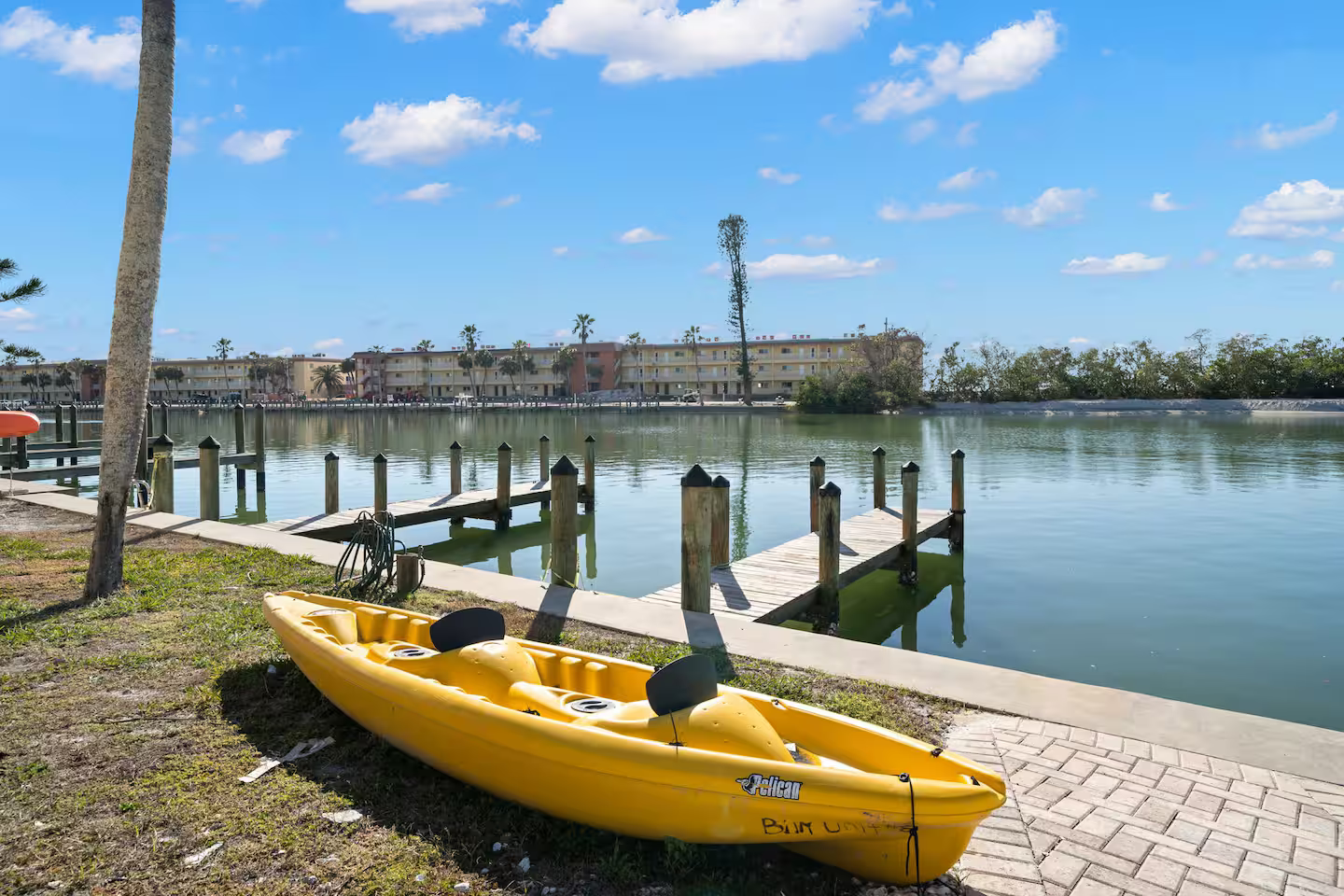 A yellow kayak is parked next to a body of water.