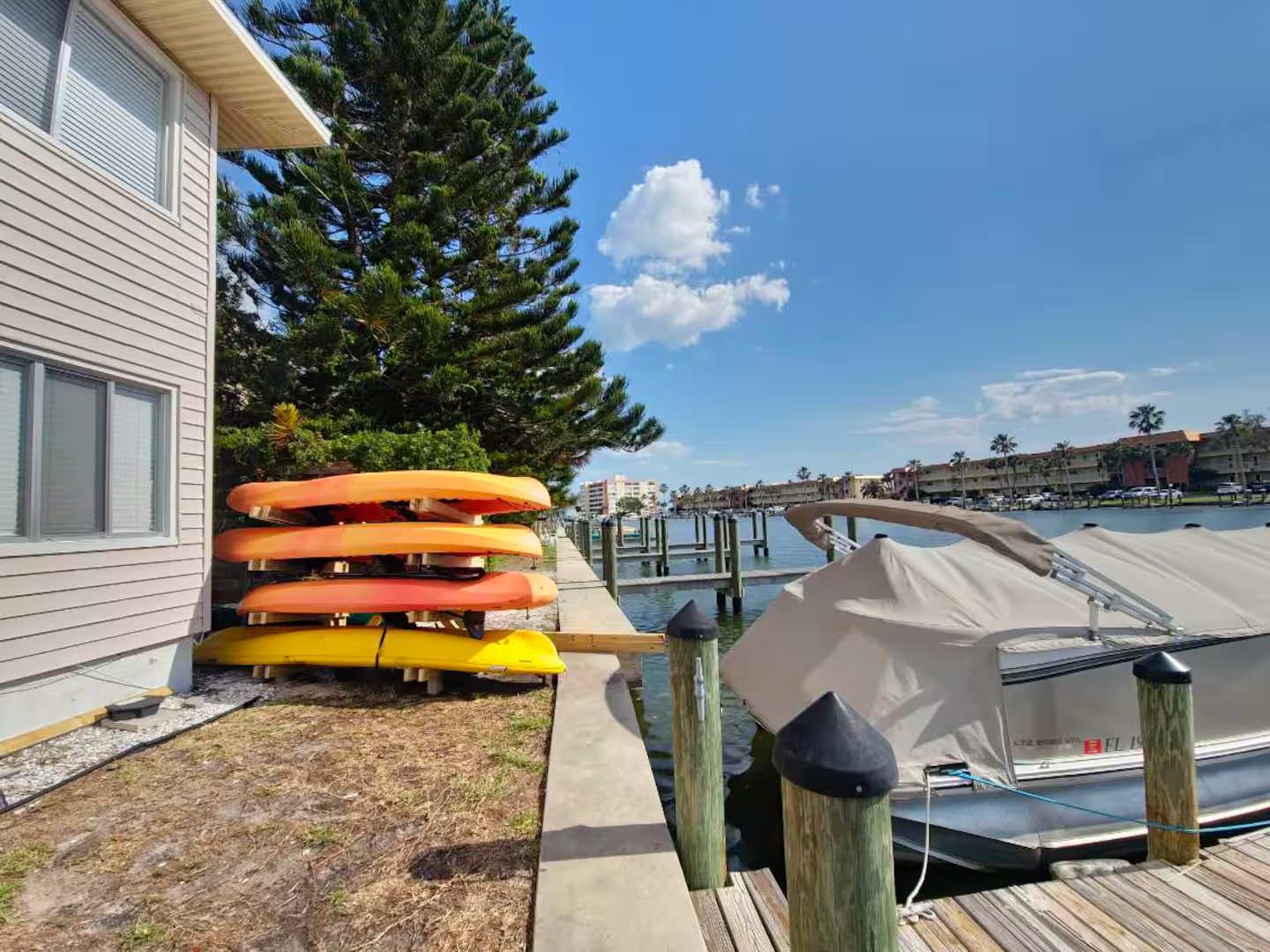 A stack of kayaks is sitting on a dock next to a house.