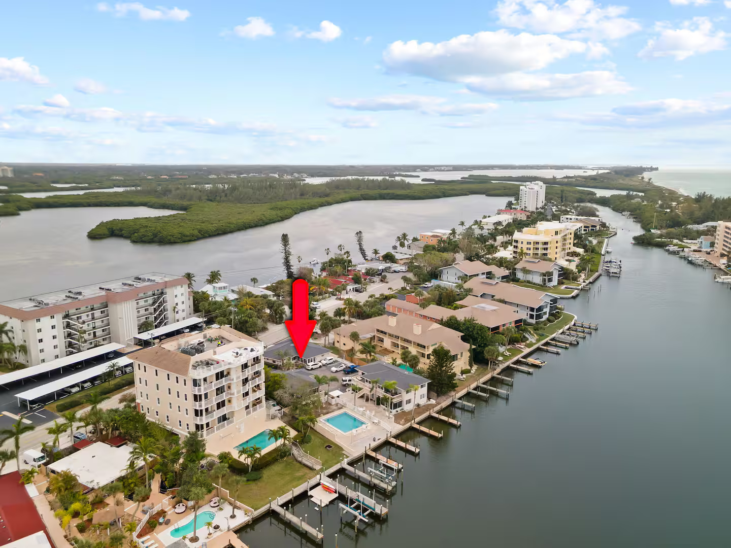 An aerial view of a residential area with a red arrow pointing to a building.