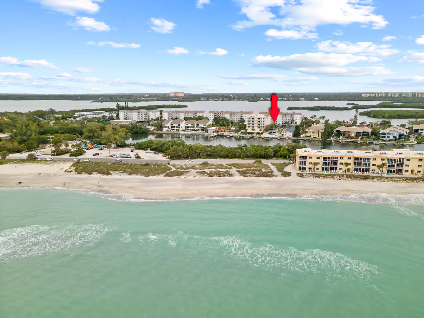 An aerial view of a beach with a red arrow pointing to a building.