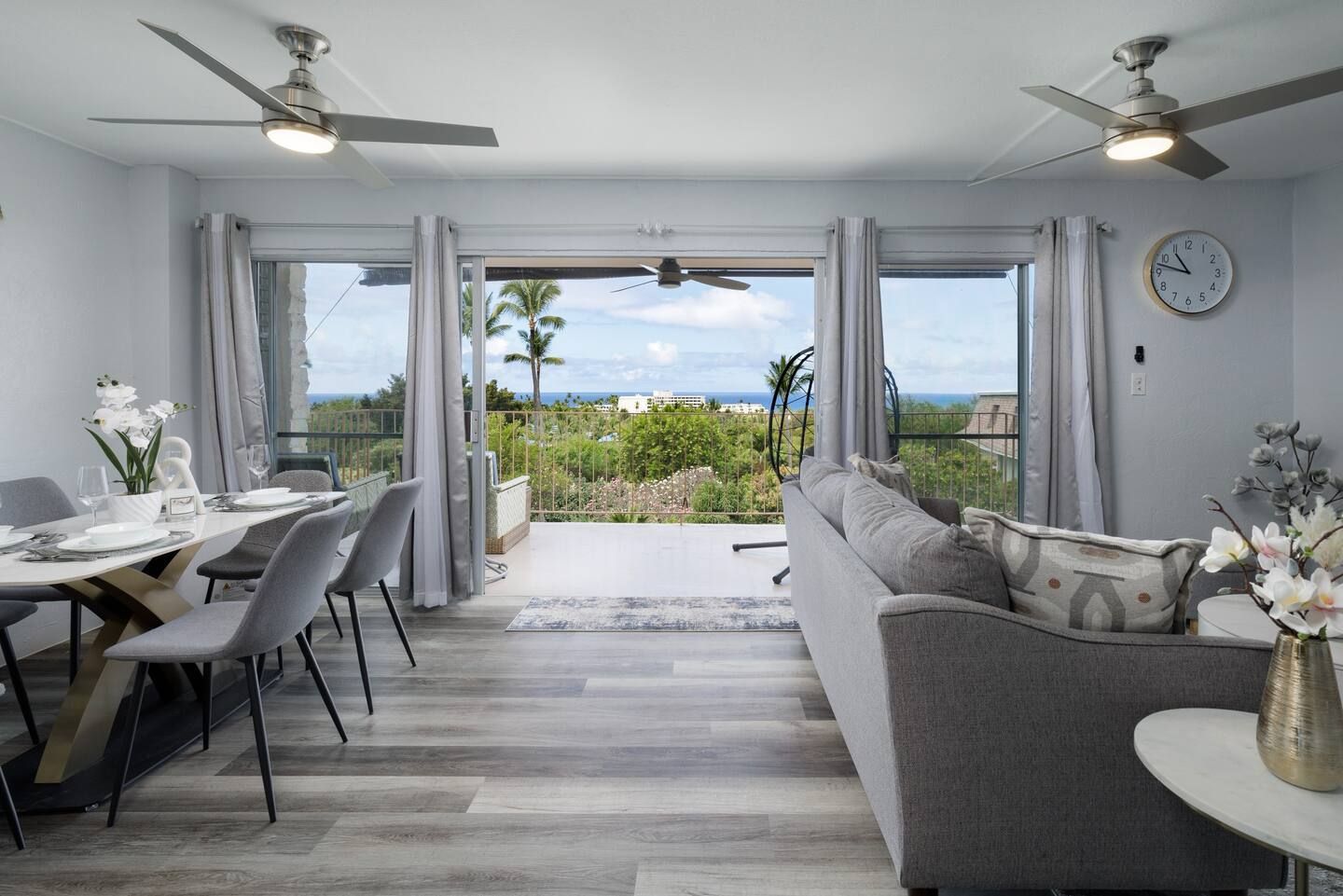 A living room with a couch , table and chairs and a ceiling fan.