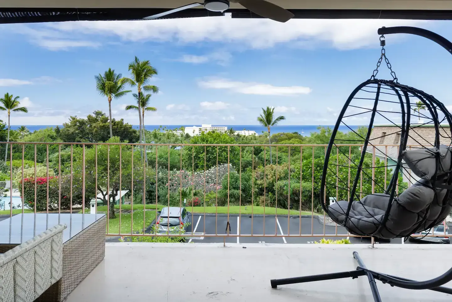A balcony with a hanging chair and a view of the ocean.