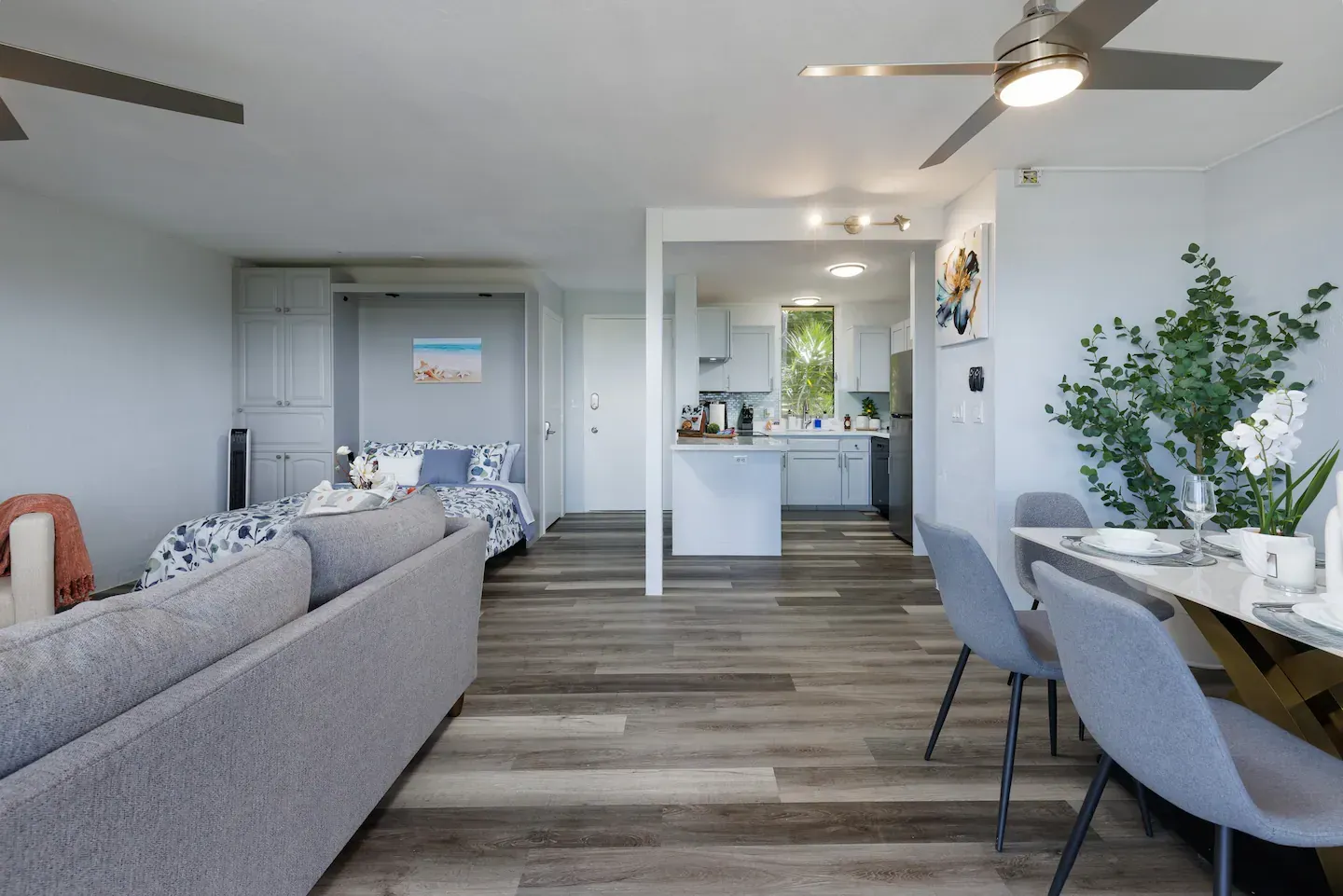 A living room with a couch , table and chairs and a ceiling fan.