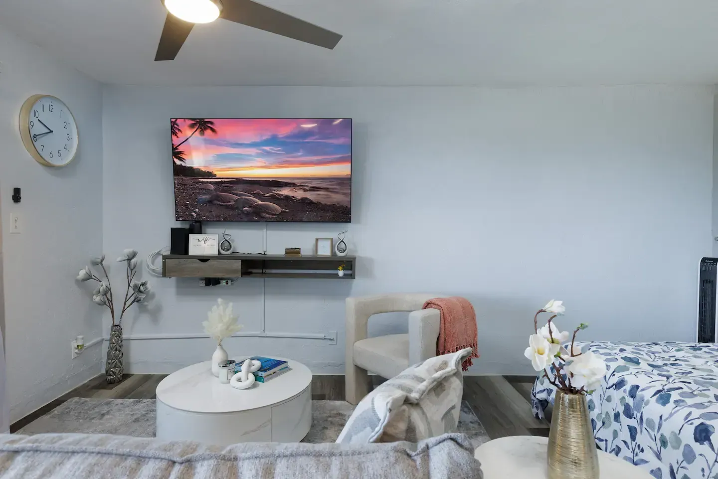 A living room with a couch , chair , table , television and a ceiling fan.