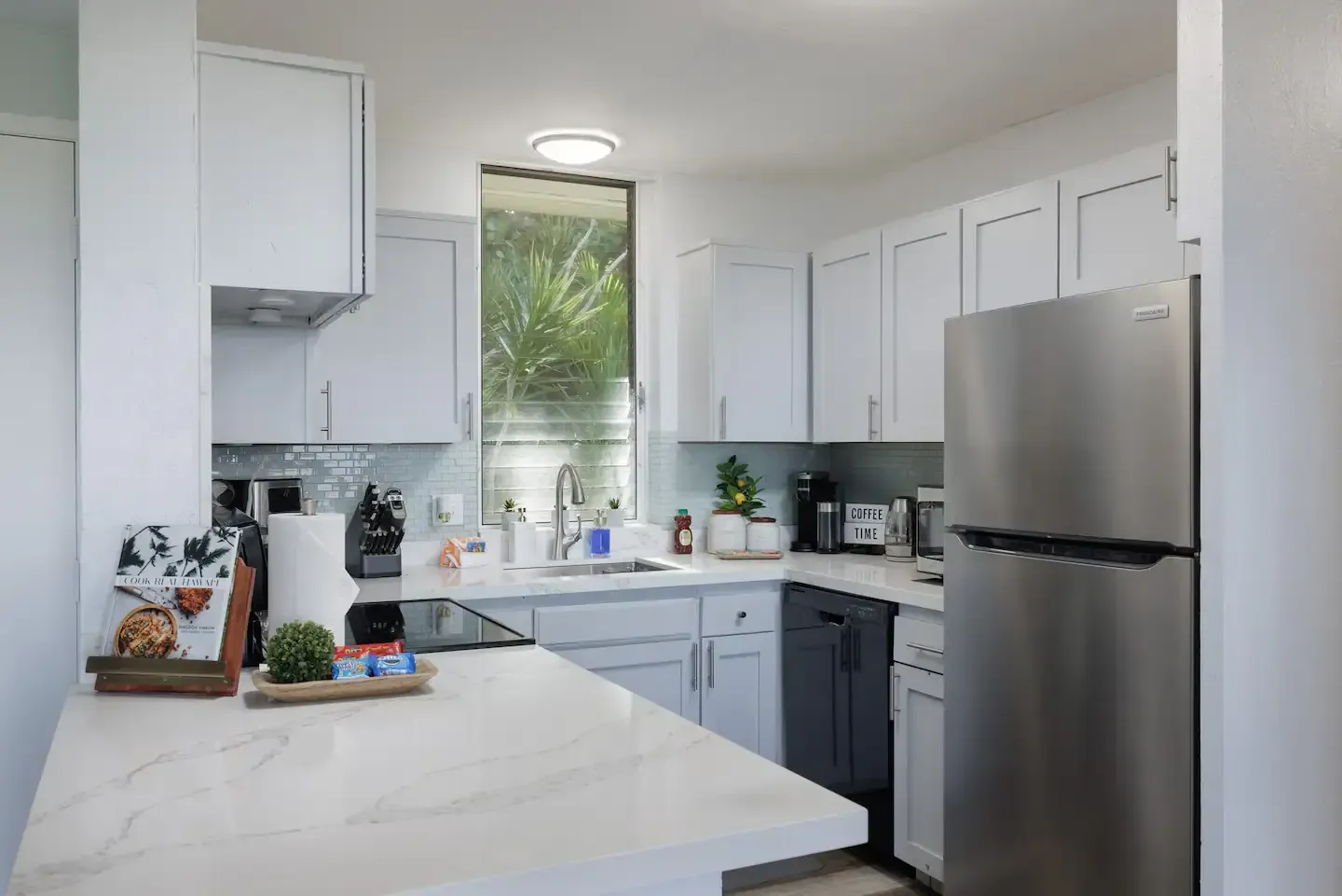 A kitchen with white cabinets and a stainless steel refrigerator.