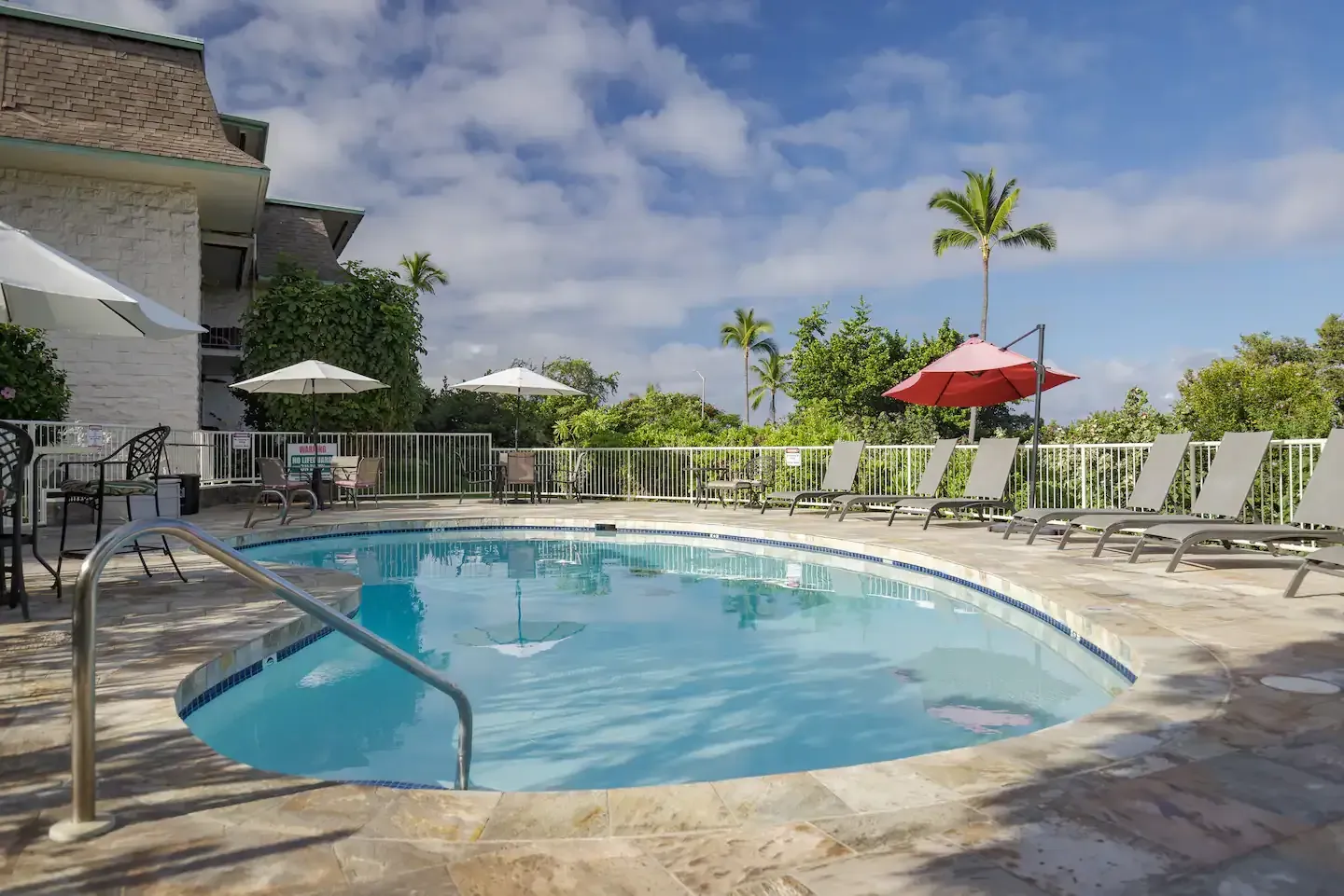 A large swimming pool with umbrellas and chairs around it.
