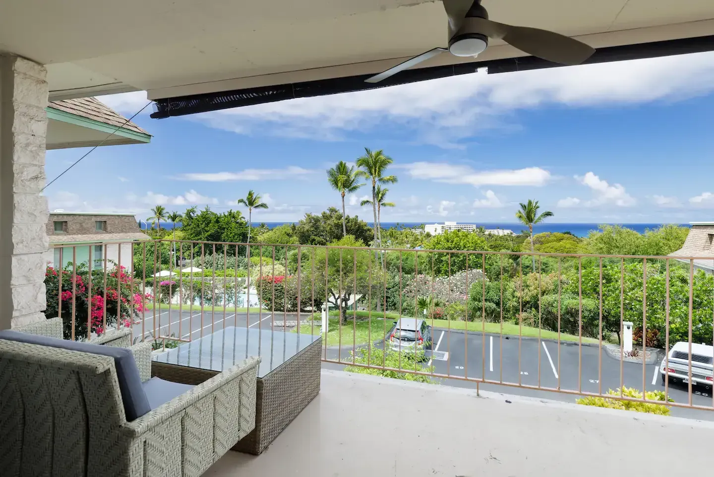 A balcony with a view of the ocean and a ceiling fan.