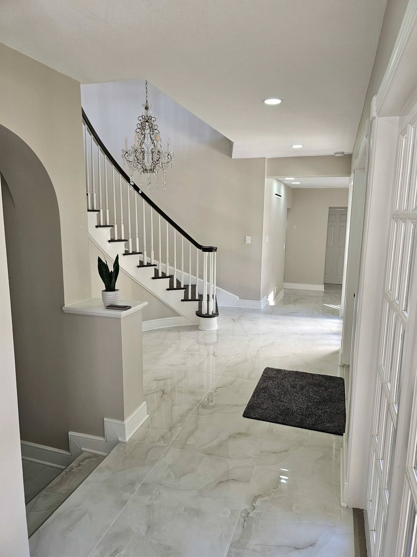 A hallway with a staircase and a chandelier hanging from the ceiling