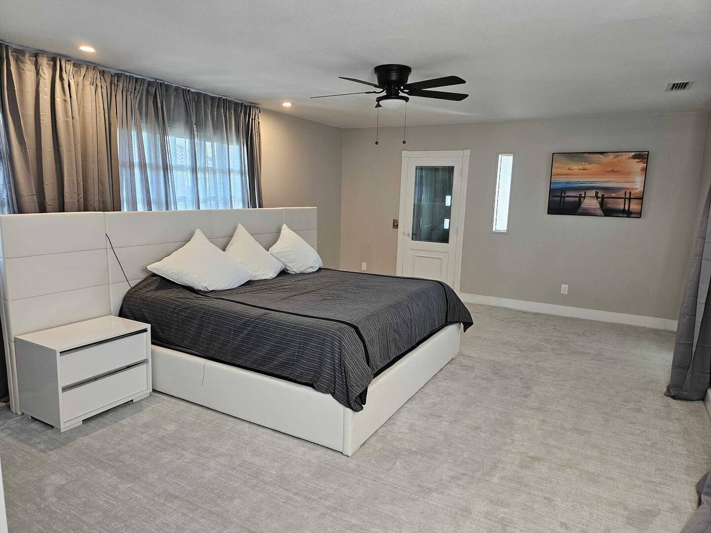 A bedroom with a large bed and a ceiling fan.