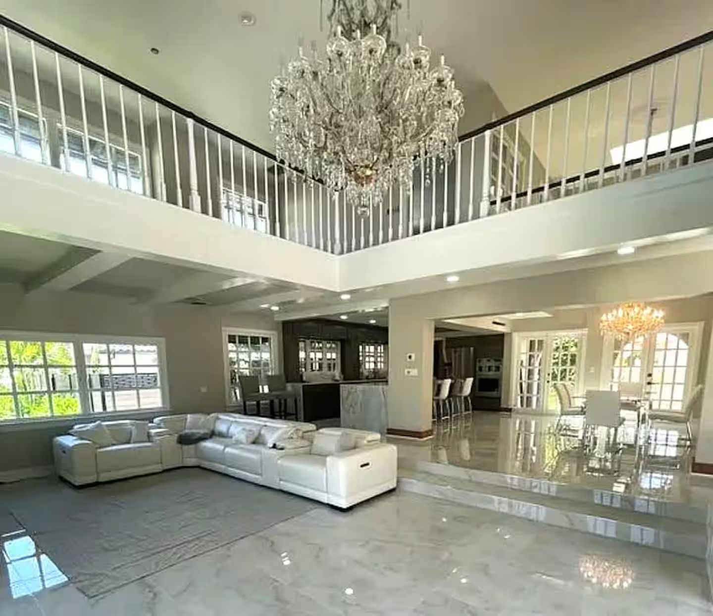 A living room with a couch , chairs , and a chandelier.