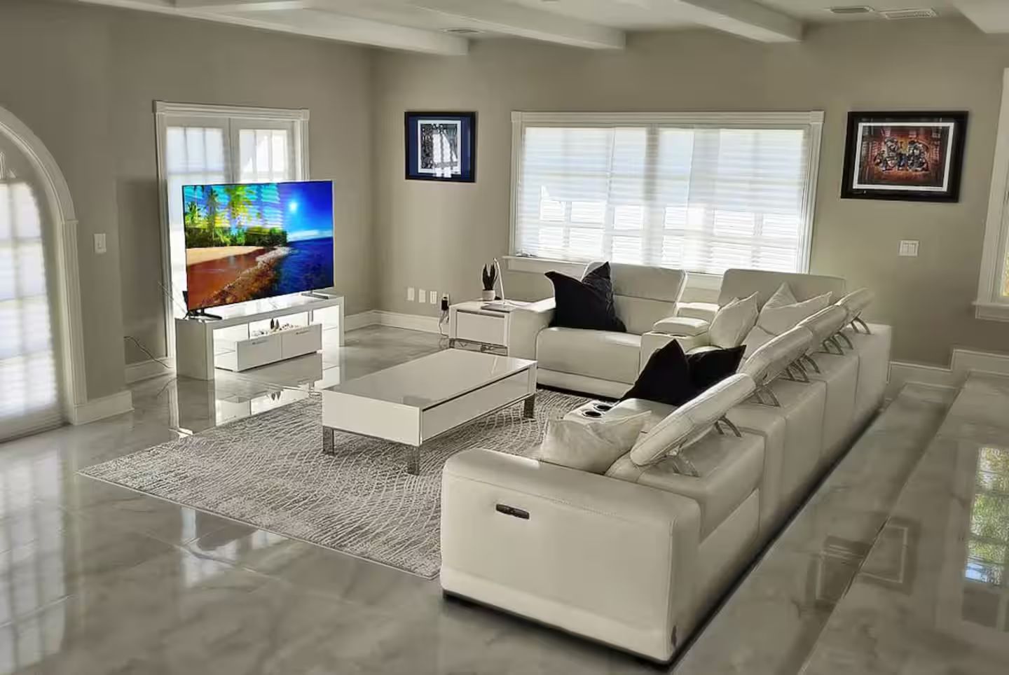A living room with white furniture and a flat screen tv.