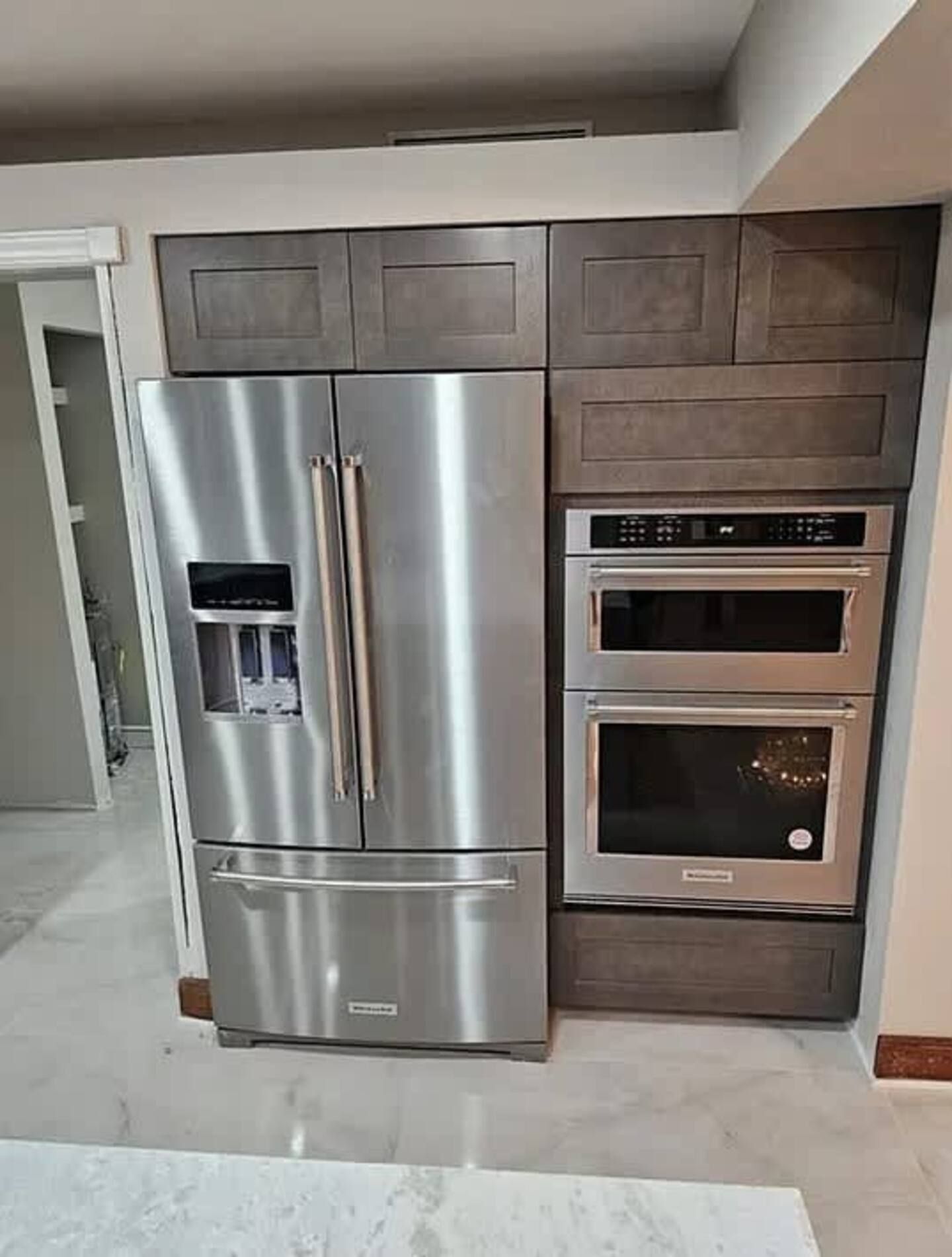 A stainless steel refrigerator , freezer , and oven are in a kitchen.
