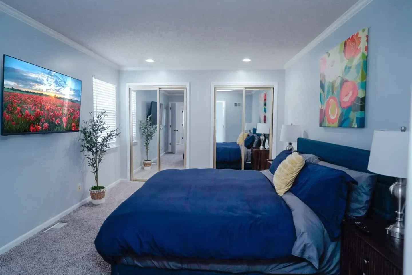 A bedroom with a large bed and a flat screen tv on the wall.