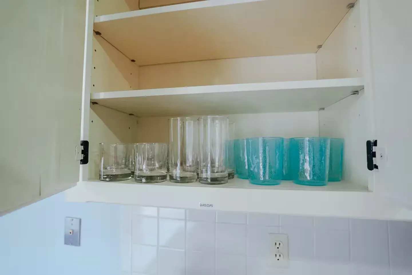 A kitchen cabinet filled with glasses and cups.