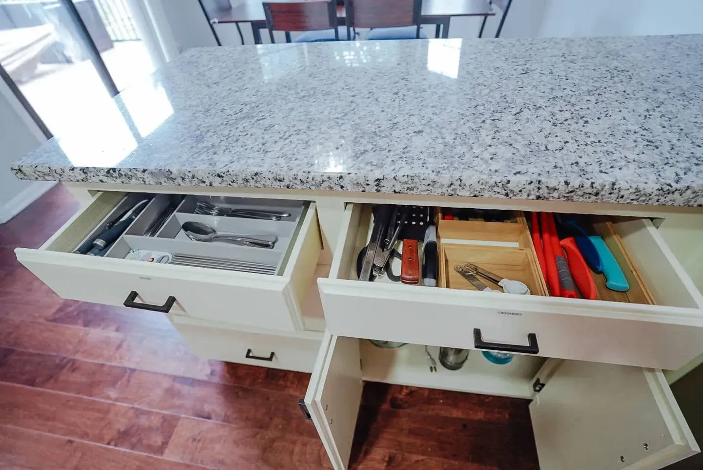A kitchen island with drawers open and utensils in them