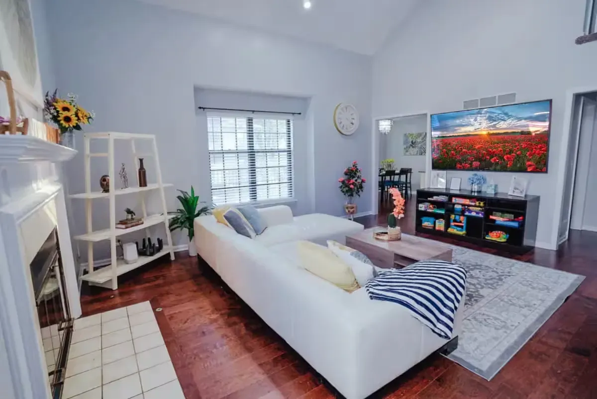 A living room with a white couch , fireplace and television.