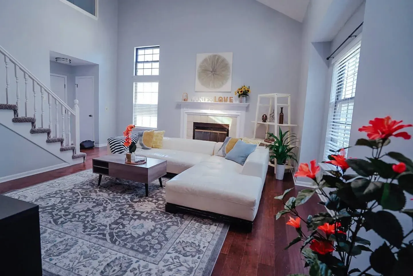 A living room with a couch , coffee table , fireplace and stairs.