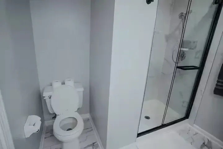 A bathroom with a toilet , shower , and paper towels.