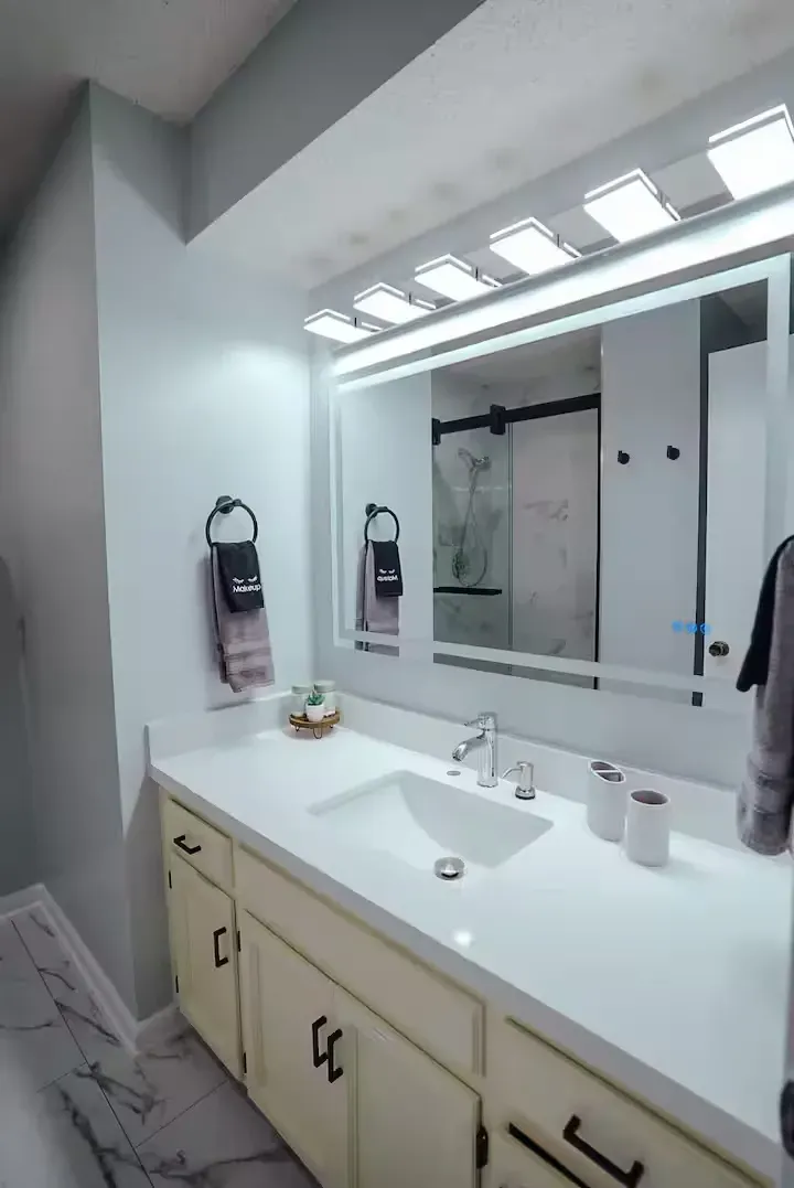 A bathroom with a sink and a large mirror.