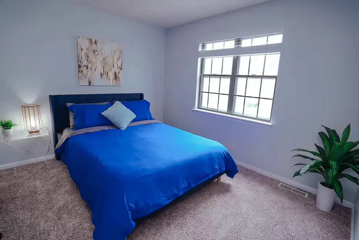 A bedroom with a blue bed and a window.