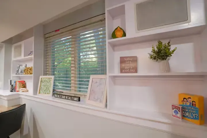 A room with white shelves and a window with blinds.