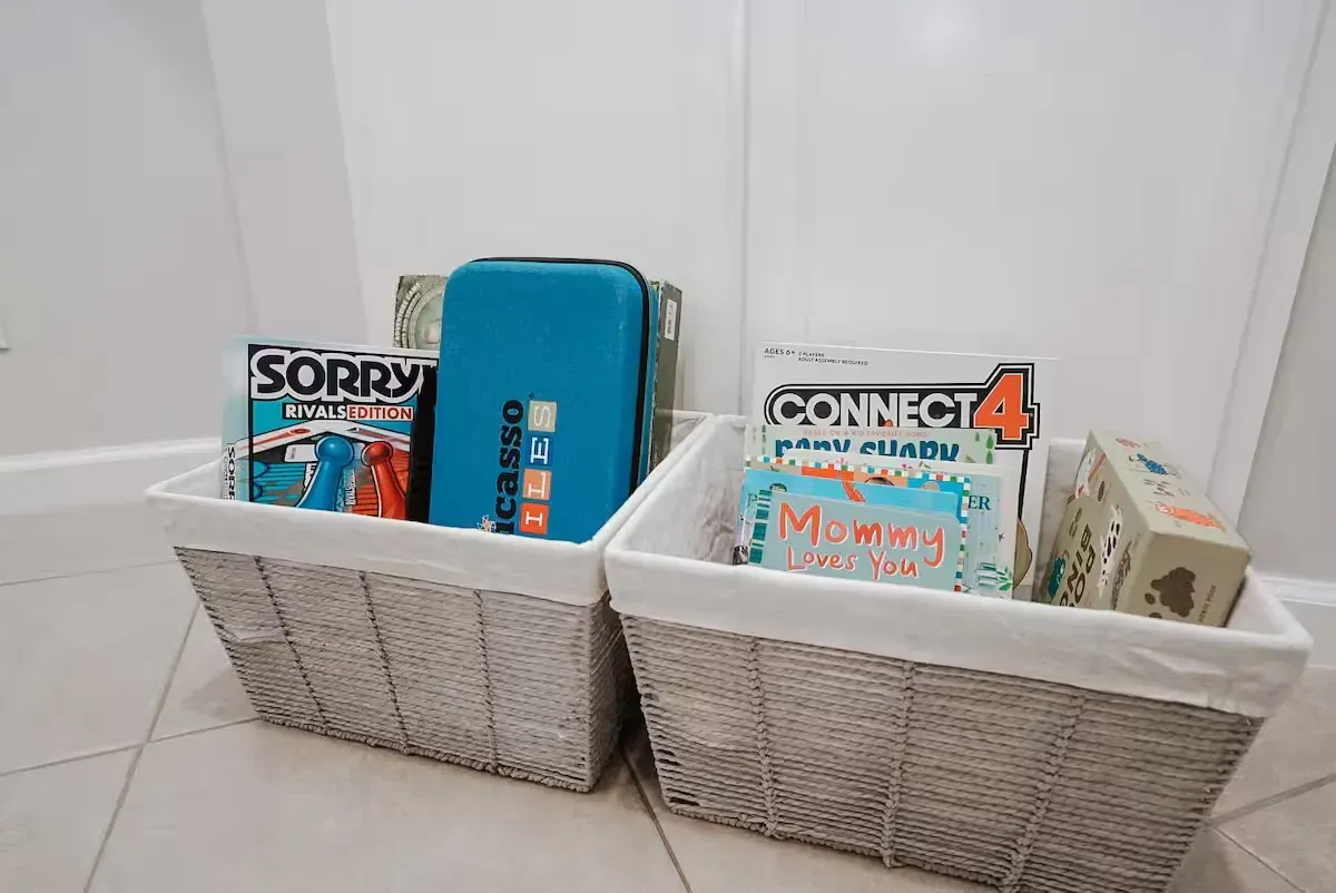 Two baskets filled with toys and games are sitting on a tiled floor.