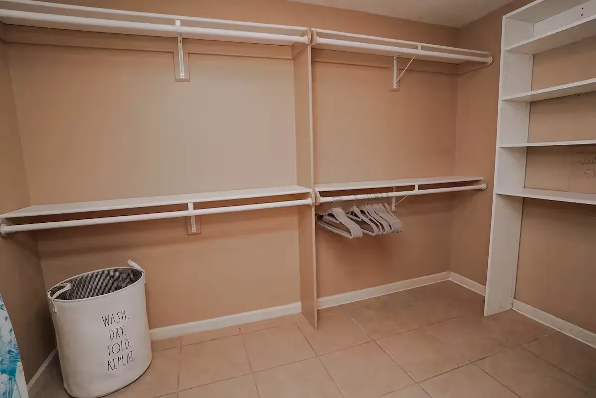 There is a laundry basket in the corner of the walk in closet.