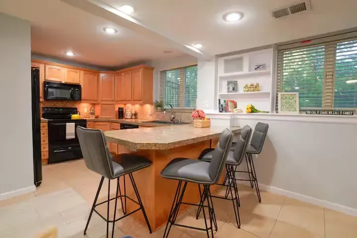 A kitchen with a large island and stools in it.