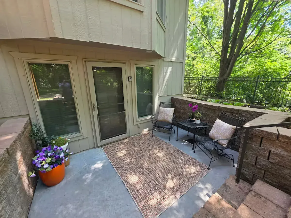 There is a patio with a table and chairs and a rug.