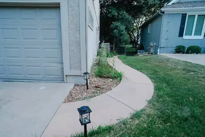A concrete walkway leading to a garage and a house