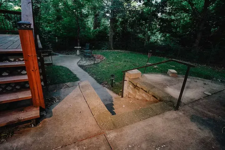 A concrete walkway leading to a wooden deck in a backyard.