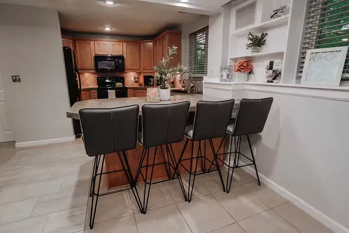 A kitchen with a table and high chairs in front of it.