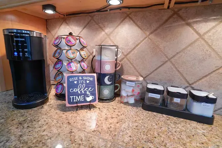 A kitchen counter with a coffee maker and a sign that says `` it 's coffee time ''.