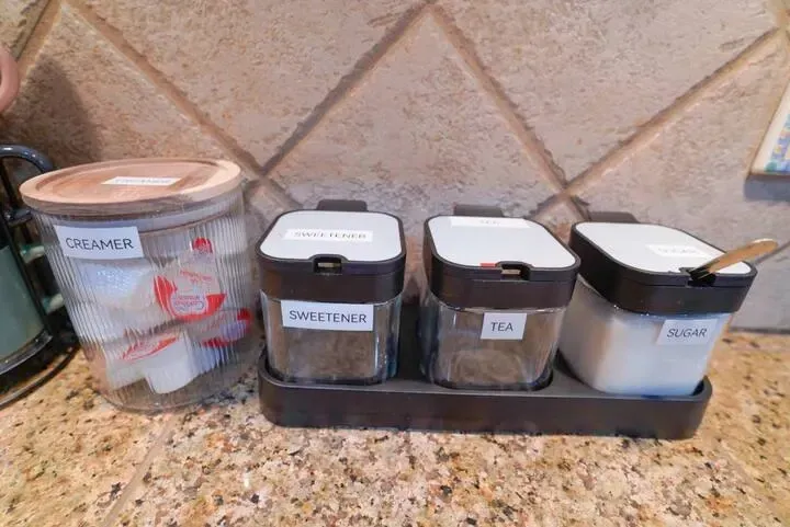 A kitchen counter with containers for sugar , salt , and pepper.