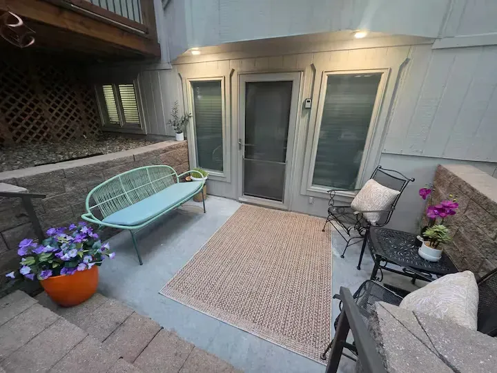 A patio with a bench , chairs , table and rug.