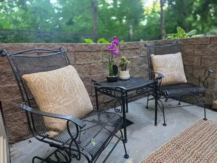 Two chairs and a table on a patio with a brick wall in the background