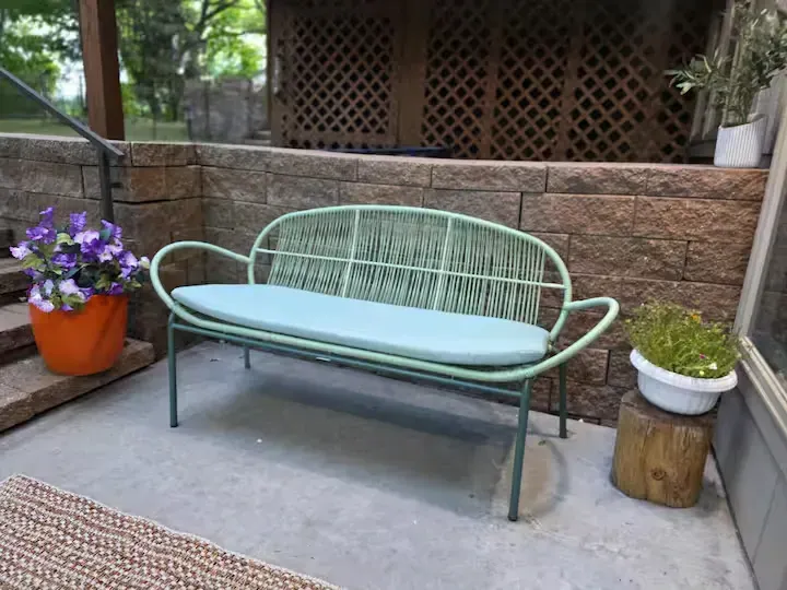 A green bench is sitting on a patio next to a potted plant.
